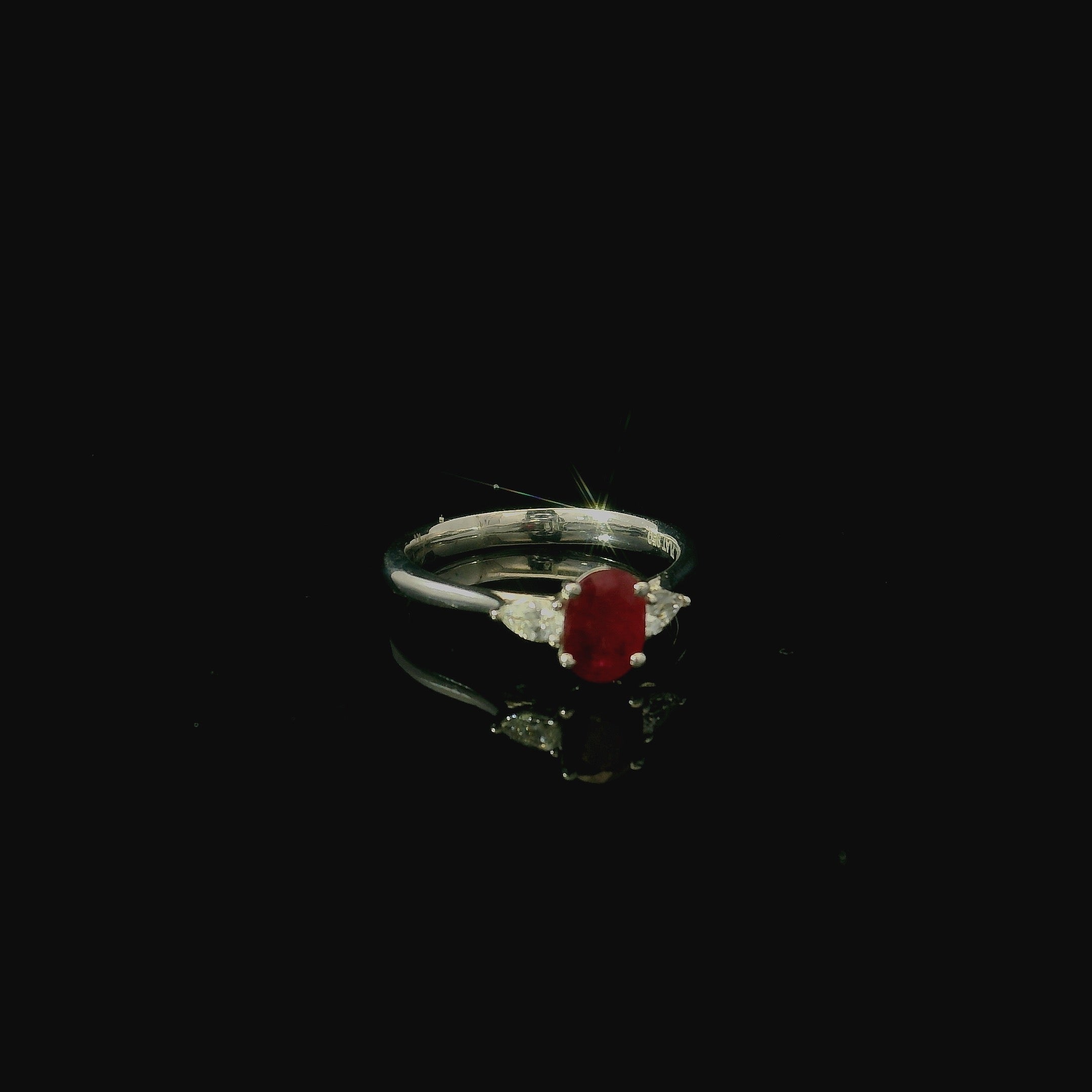 platinum ring with oval cut mid red ruby gemstone. pear cut diamonds 