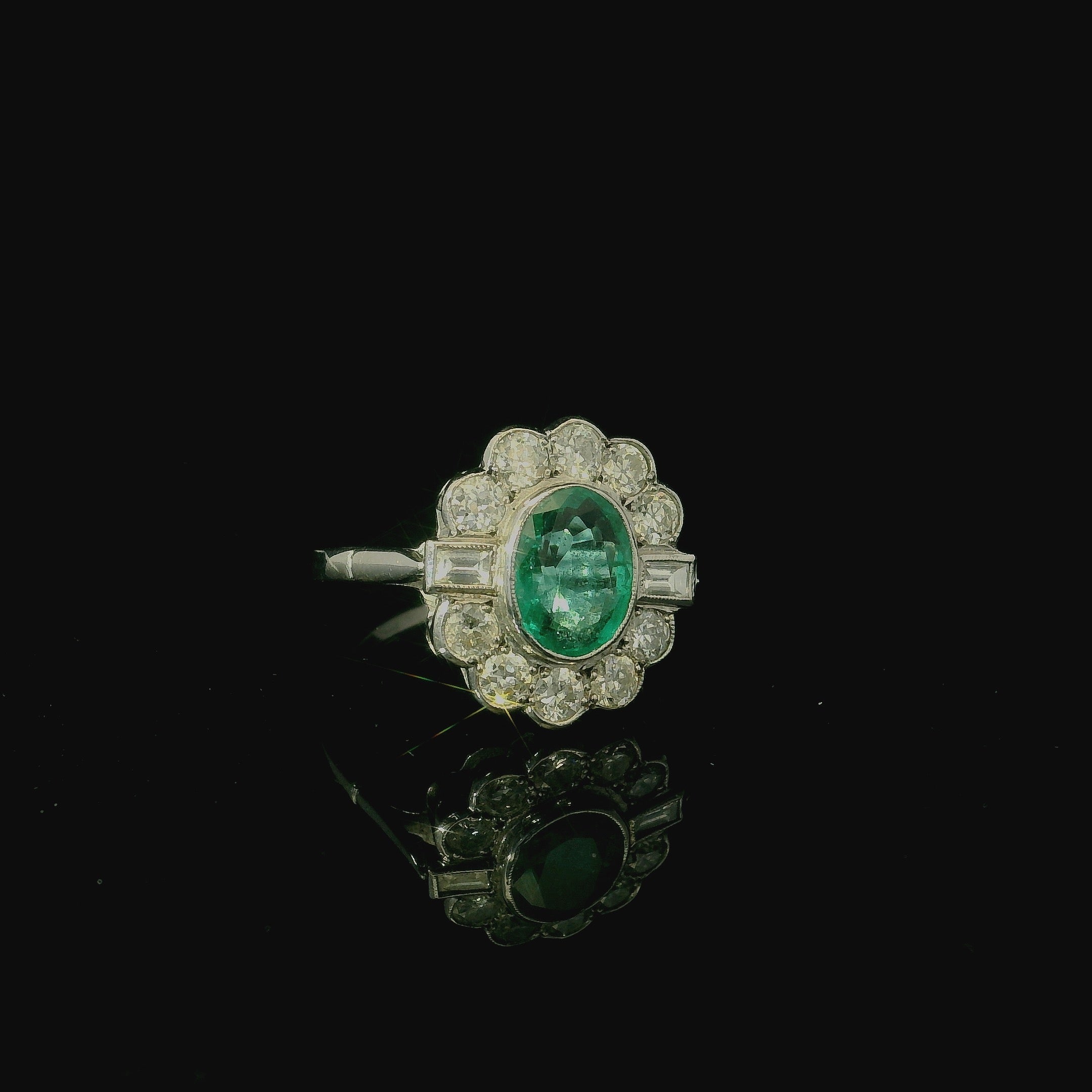 white gold ring. oval cut emerald stone. diamond cluster. daisy shaped ring. antique jewellery. vintage engagement rings. 